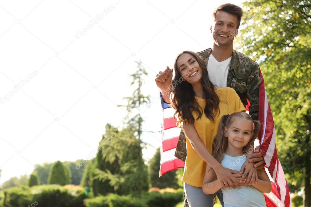 Man in military uniform with American flag and his family at sunny park