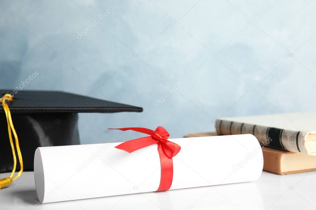 Student's graduation diploma on white wooden table against light blue background