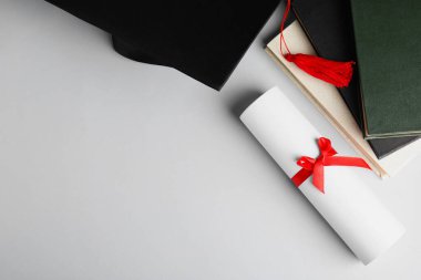 Mezuniyet şapkası, kitaplar ve öğrenci diploması beyaz arka plan, üst görünüm. Metin için boşluk