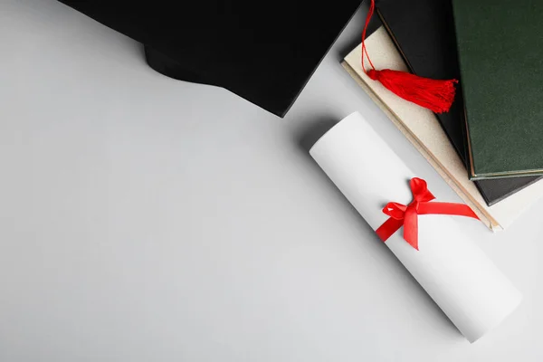 Graduation hat, books and student's diploma white background, top view. Space for text — Stockfoto