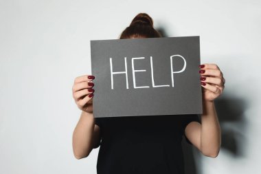 Elinde kelime kartı olan genç bir kadın. Arka planda ışığa karşı yardım.