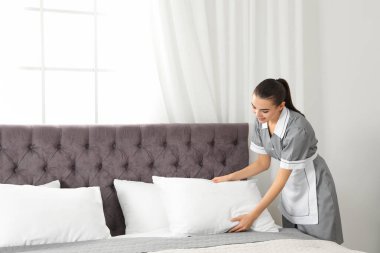 Otel odasında yatak yapma genç Oda hizmetçisi. Metin için yer