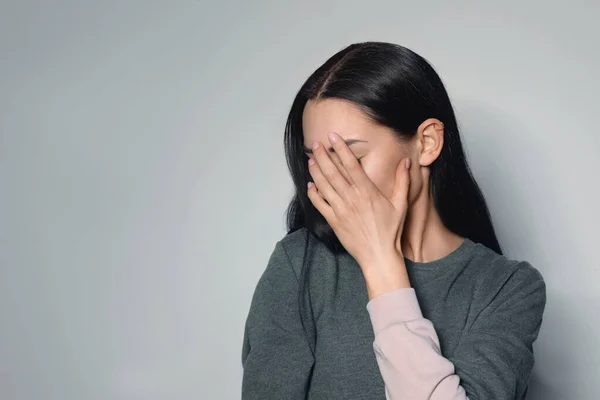Aufgebrachte junge Frau weint vor hellem Hintergrund. Raum für Text — Stockfoto