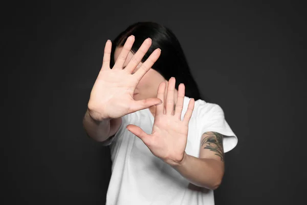 Jovem mulher fazendo parar gesto contra fundo escuro, foco na mão — Fotografia de Stock