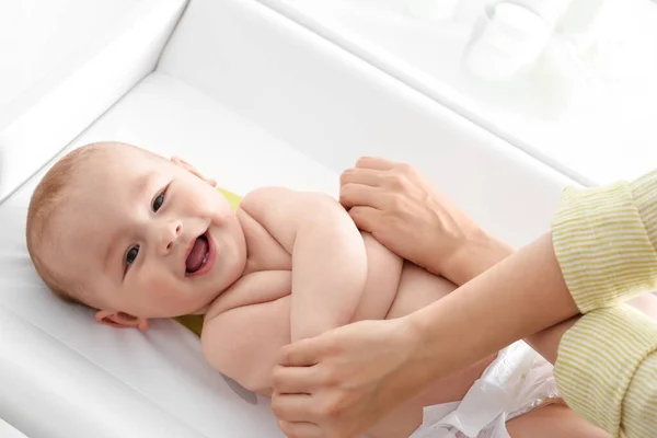 Junge Frau massiert süßes Baby auf Wickeltisch — Stockfoto