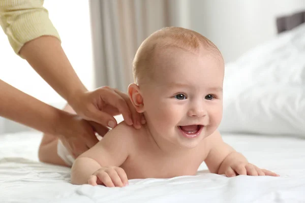 Młoda kobieta masażu cute little baby na łóżku wewnątrz — Zdjęcie stockowe