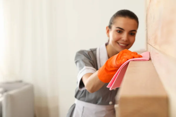 Young chambermaid wiping dust from furniture with rag in hotel room, closeup. Space for text — Stock Photo, Image