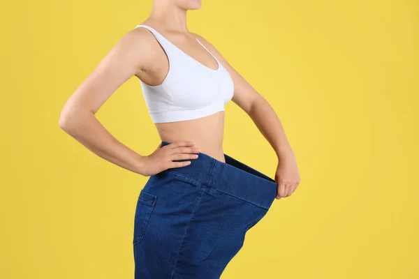 Jovem magro mulher vestindo jeans oversized no fundo amarelo, close-up — Fotografia de Stock