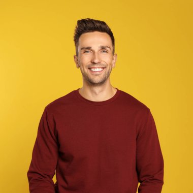 Sarı arka planda sweatshirt giyen mutlu genç adam. Kış mevsimi