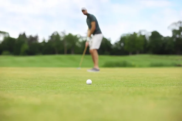Чоловік грає в гольф на зеленій трасі, м'яч у фокусі — стокове фото