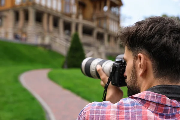 Фотограф фотографує красивий будинок з професійною камерою на відкритому повітрі — стокове фото