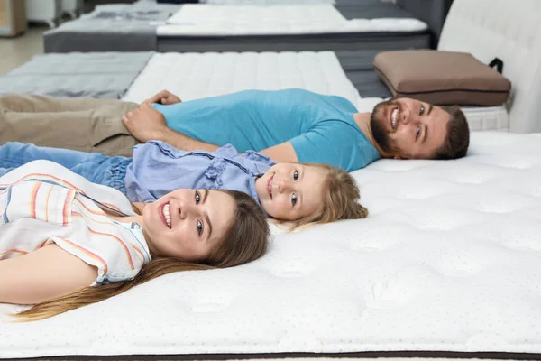 Glückliche Familie liegt auf neuer orthopädischer Matratze im Geschäft — Stockfoto