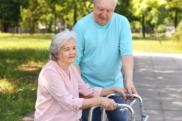 Ηλικιωμένος άνθρωπος βοηθώντας τη γυναίκα του με το πλαίσιο πεζοπορίας σε εξωτερικούς χώρους — Φωτογραφία Αρχείου