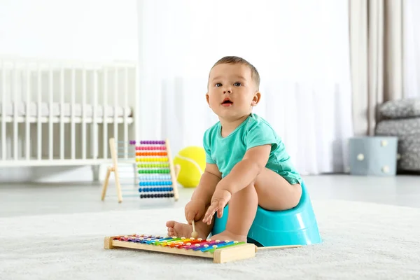 Kleiner Junge mit Xylophon sitzt zu Hause auf Töpfchen — Stockfoto