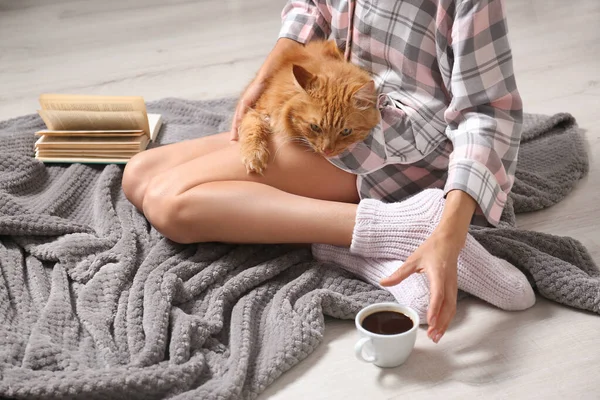 Mujer con lindo gato rojo y libro sobre manta gris en casa, vista de cerca. Espacio para texto — Foto de Stock