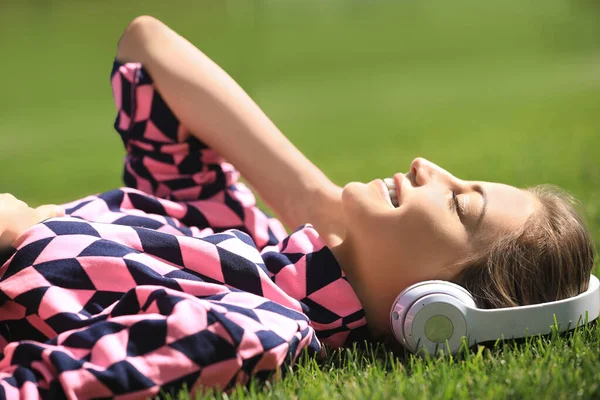 Junge Frau mit Kopfhörern hört Musik im Park — Stockfoto