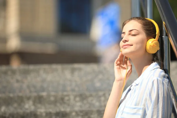 Junge Frau mit Kopfhörern, die auf der Treppe Musik hört. Raum für Text — Stockfoto