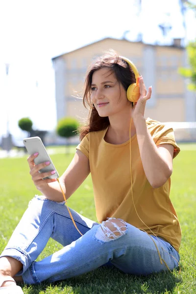 Junge Frau mit Kopfhörern hört Musik im Park — Stockfoto