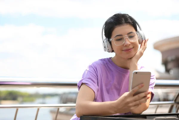 Young woman with headphones listening to music outdoors. Space for text — Stock Photo, Image