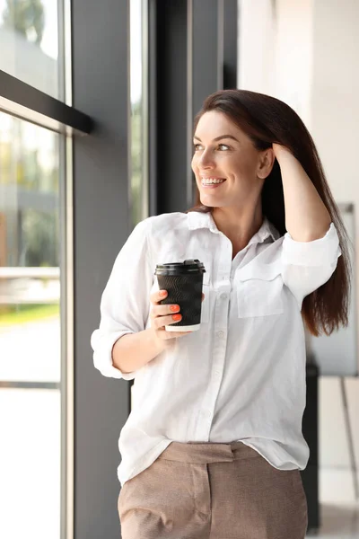 Portrait of female business trainer with cup of coffee indoors