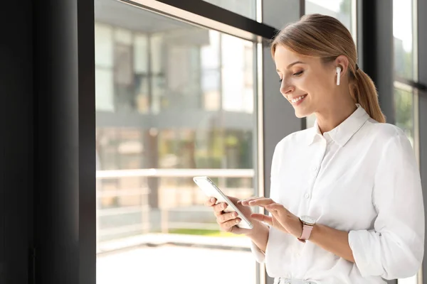 Portrait of female business trainer with smartphone indoors