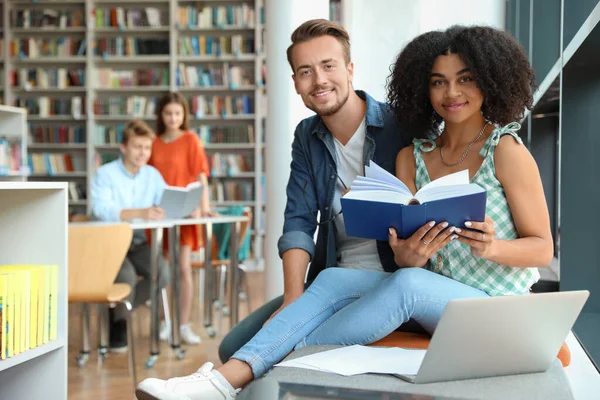 Jovens que estudam juntos na biblioteca moderna — Fotografia de Stock