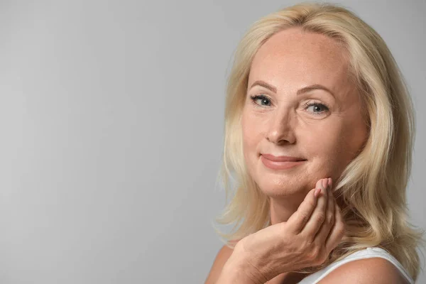 Retrato de una hermosa mujer madura con la piel perfecta sobre fondo gris. Espacio para texto — Foto de Stock