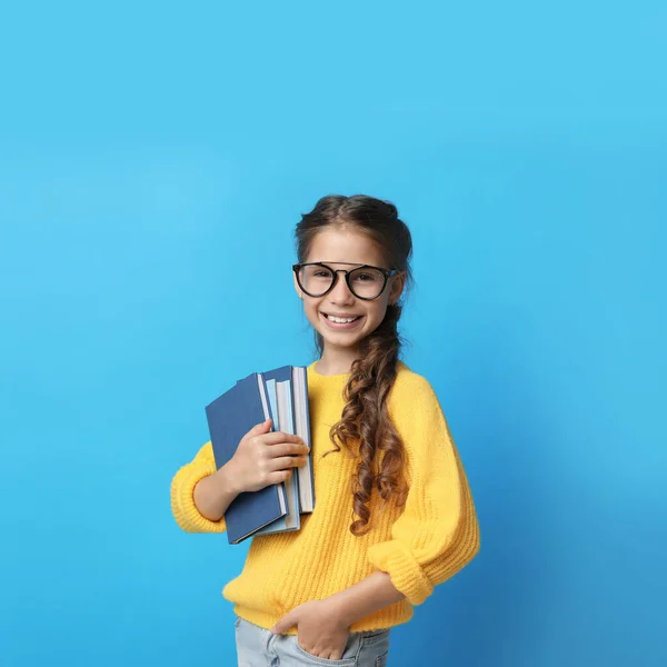 Menina bonito com óculos e livros sobre fundo azul. Conceito de leitura — Fotografia de Stock