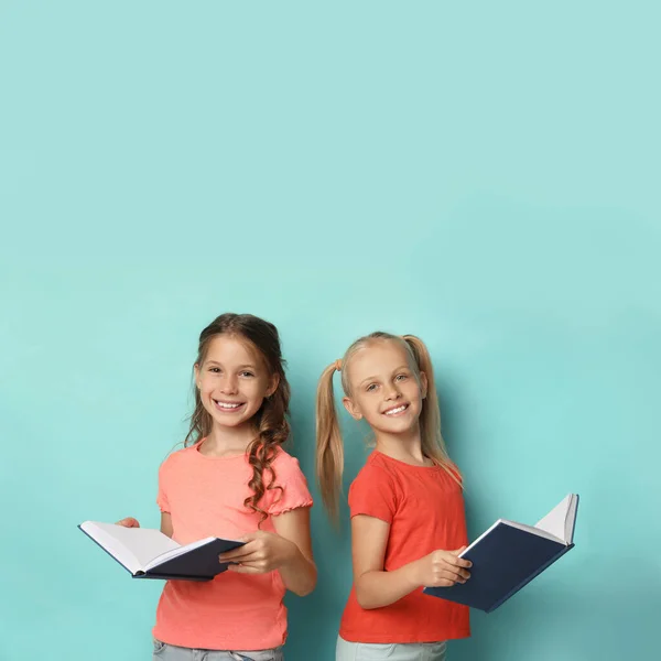 Portrét malých dívek, které čtou knihy na tyrkysovém pozadí — Stock fotografie