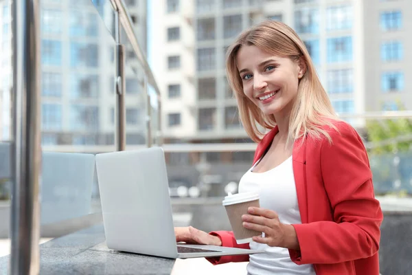 街の通りにノートパソコンとコーヒーカップを持つ美しいビジネス女性 — ストック写真