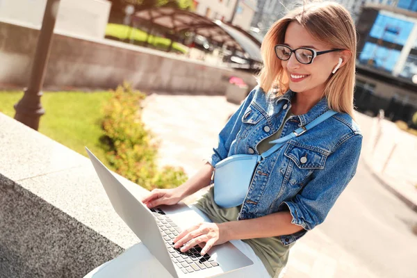 Hermosa mujer usando el ordenador portátil en la ciudad en el día soleado — Foto de Stock