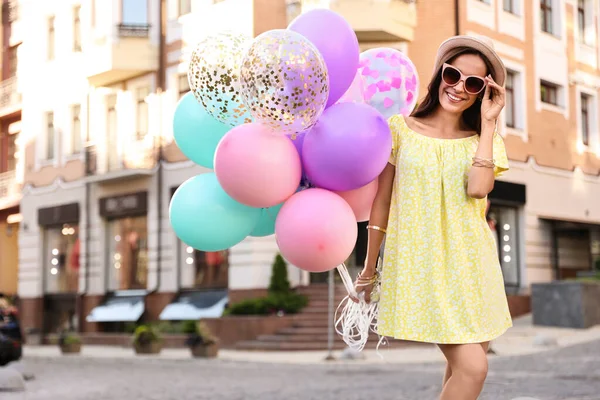 Hermosa mujer joven con globos de color en la calle de la ciudad — Foto de Stock