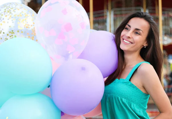 Atractiva joven con globos de color cerca del carrusel — Foto de Stock