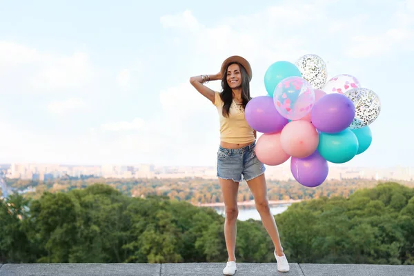 Vrolijke jonge vrouw met kleurballonnen in het park — Stockfoto