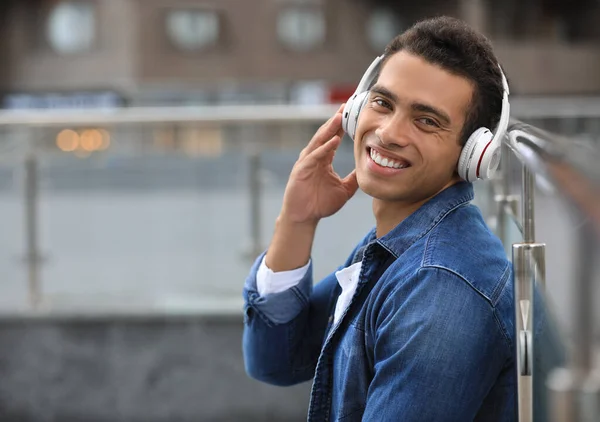 Beau jeune homme afro-américain avec écouteurs écoutant de la musique dans la rue de la ville. Espace pour le texte — Photo