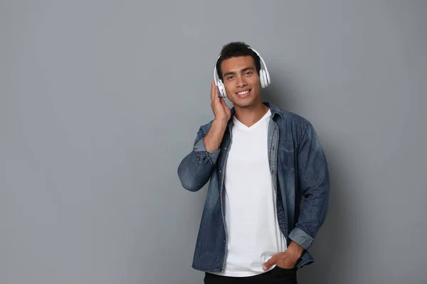 Guapo joven afroamericano con auriculares escuchando música sobre fondo gris. Espacio para texto —  Fotos de Stock