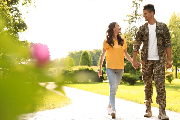 身穿军服的男人和他的女朋友在阳光灿烂的公园散步 — 图库照片