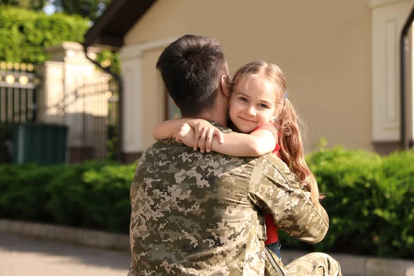 Батько у військовій формі обіймає маленьку доньку на відкритому повітрі — стокове фото