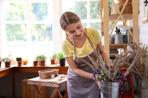 Mujer joven cuidando plantas caseras en la mesa de madera en la tienda — Foto de Stock