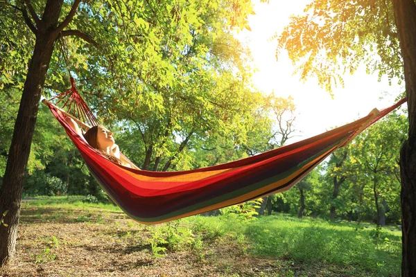 Jeune femme reposant dans un hamac confortable au jardin vert — Photo