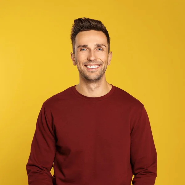 Glad ung man i tröja på gul bakgrund. Vintersäsong — Stockfoto