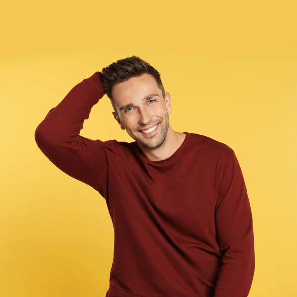 Glad ung man i tröja på gul bakgrund. Vintersäsong — Stockfoto