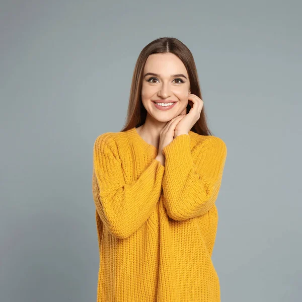 Hermosa mujer joven en suéter amarillo sobre fondo gris. Temporada de invierno — Foto de Stock