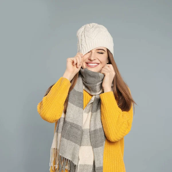 Jovem feliz em roupas quentes no fundo cinza. Temporada de Inverno — Fotografia de Stock