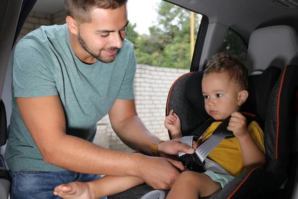 Vater schnallt seinen Sohn mit Sicherheitsgurt im Kindersitz an Familienurlaub — Stockfoto