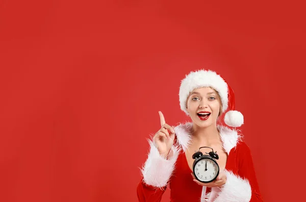 Hermosa chica Santa con despertador sobre fondo rojo, espacio para texto. Nochebuena —  Fotos de Stock