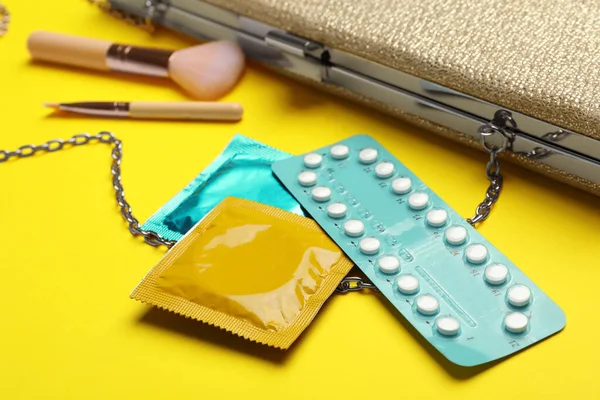 Préservatifs et pilules contraceptives sur fond jaune, gros plan. Concept de sexe sûr — Photo