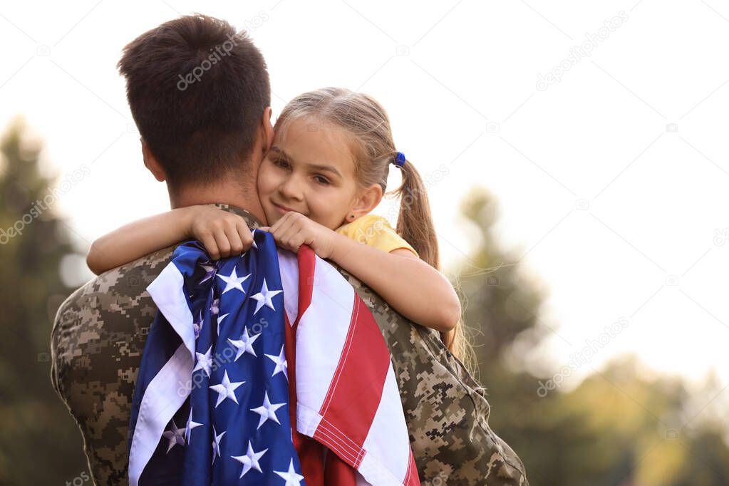 Father in military uniform with American flag and his daughter at sunny park