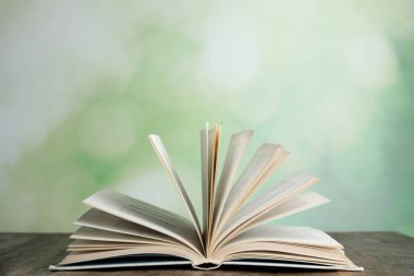 Bulanık yeşil arka plana karşı ahşap masa üzerinde kitabı aç