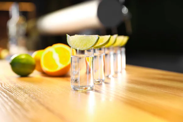 Colpi di vodka e fette di lime sul bancone del bar in legno — Foto Stock